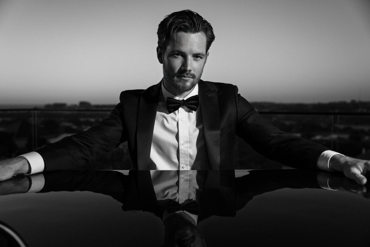 Curtis hosting beside the piano, black and white