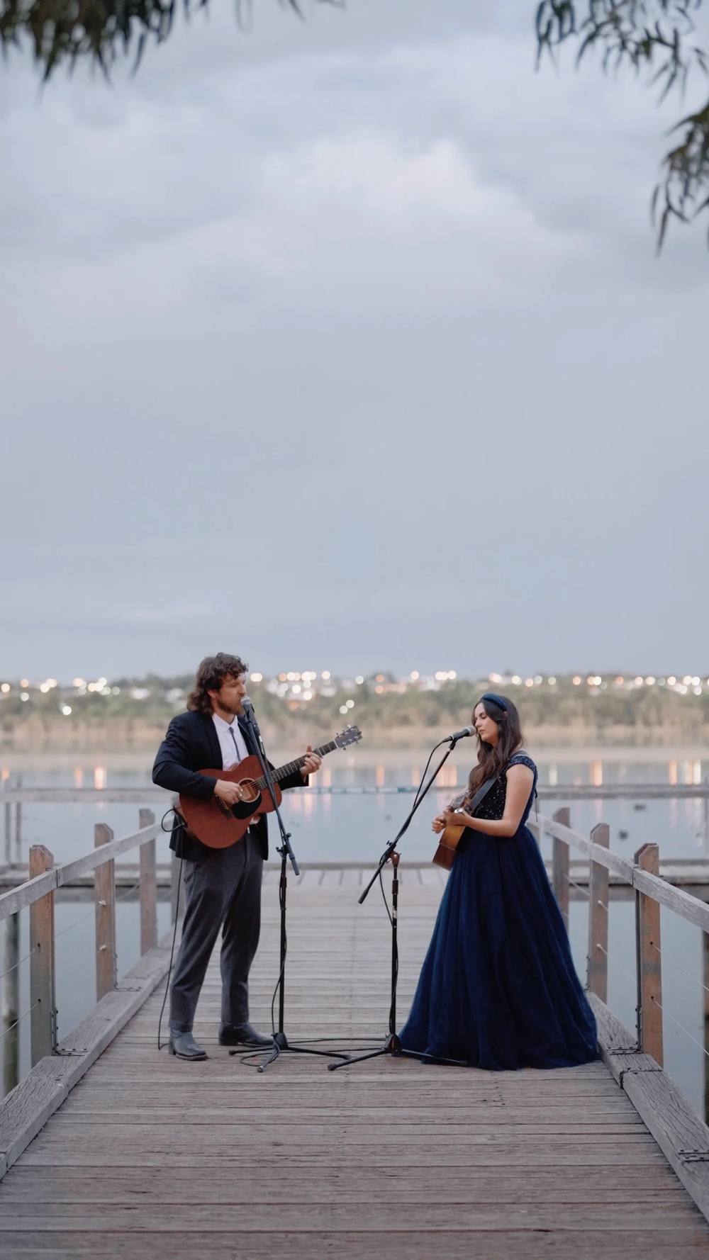 Johannah performing as a duo on a jetty at dusk